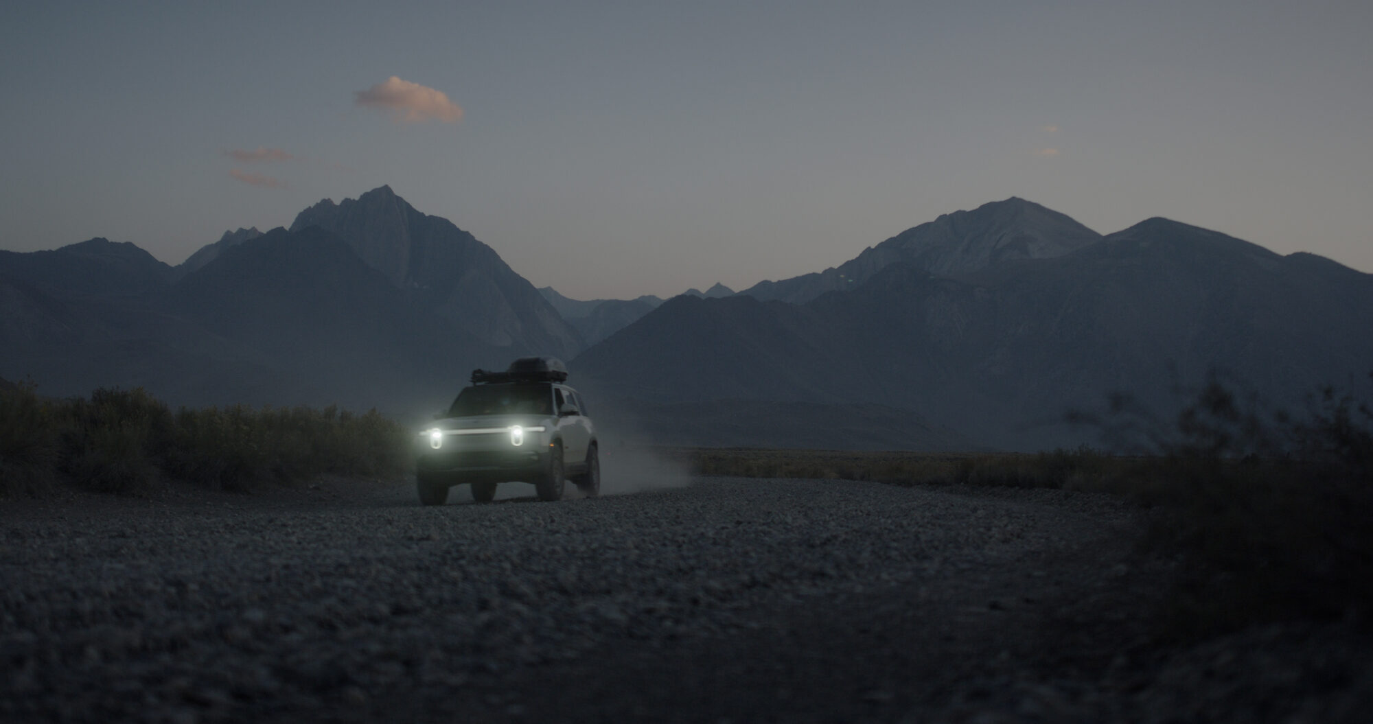 A truck crossing the desert at dusk below the Eastern Sierra